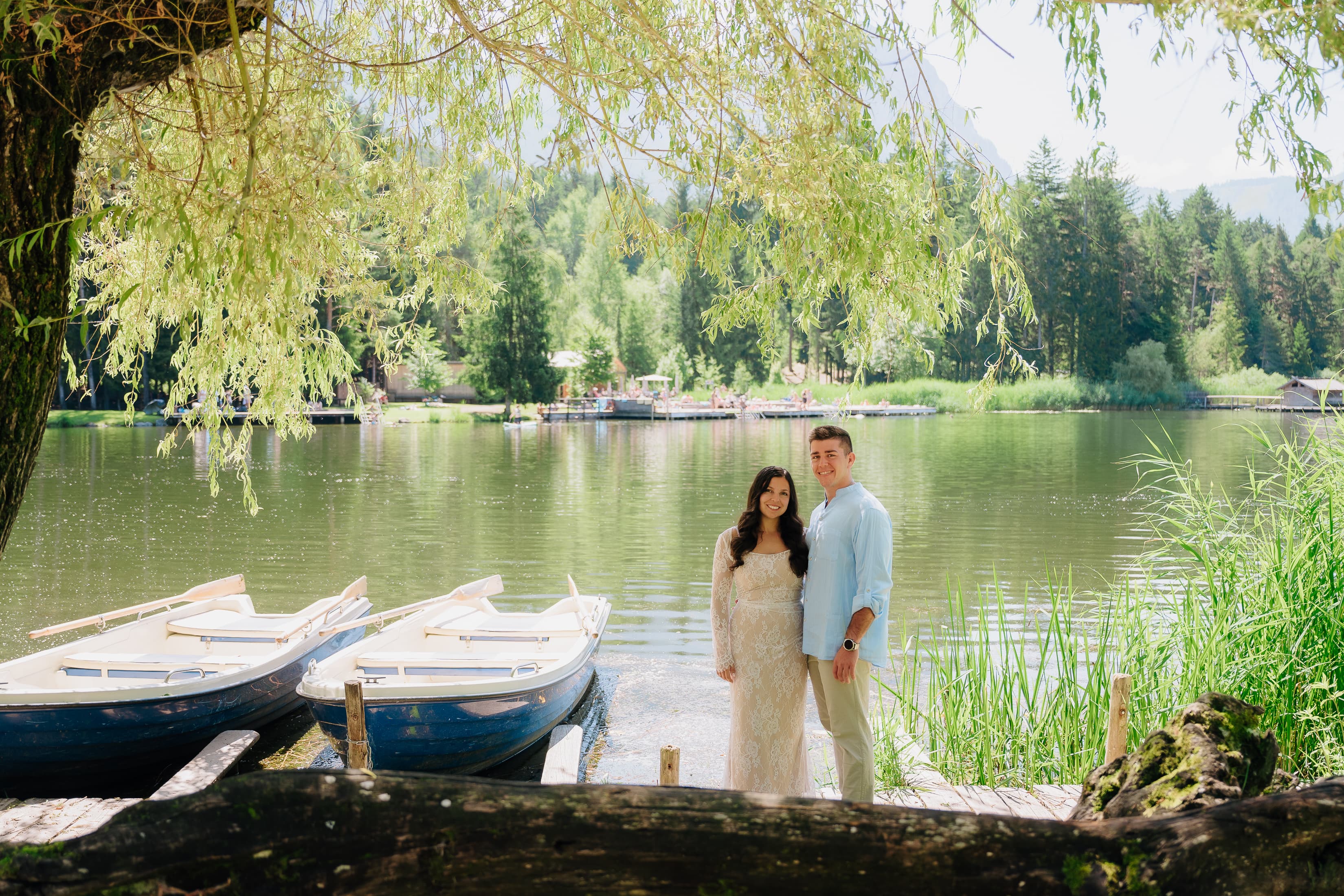 JT and Nicole standing by a lake with rowboats nearby.