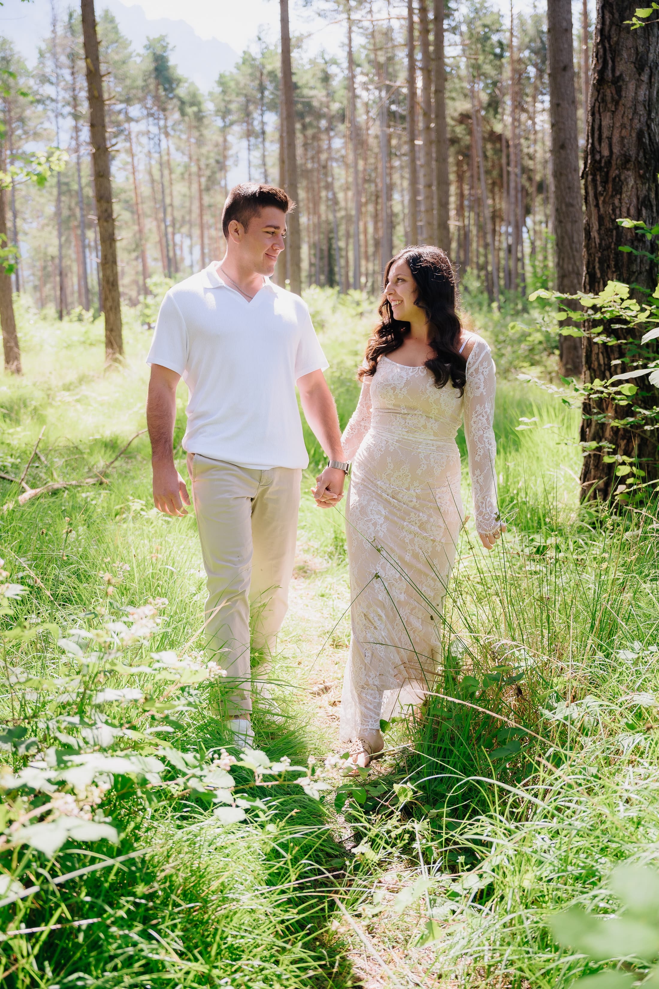 JT and Nicole walking hand in hand through the trees.
