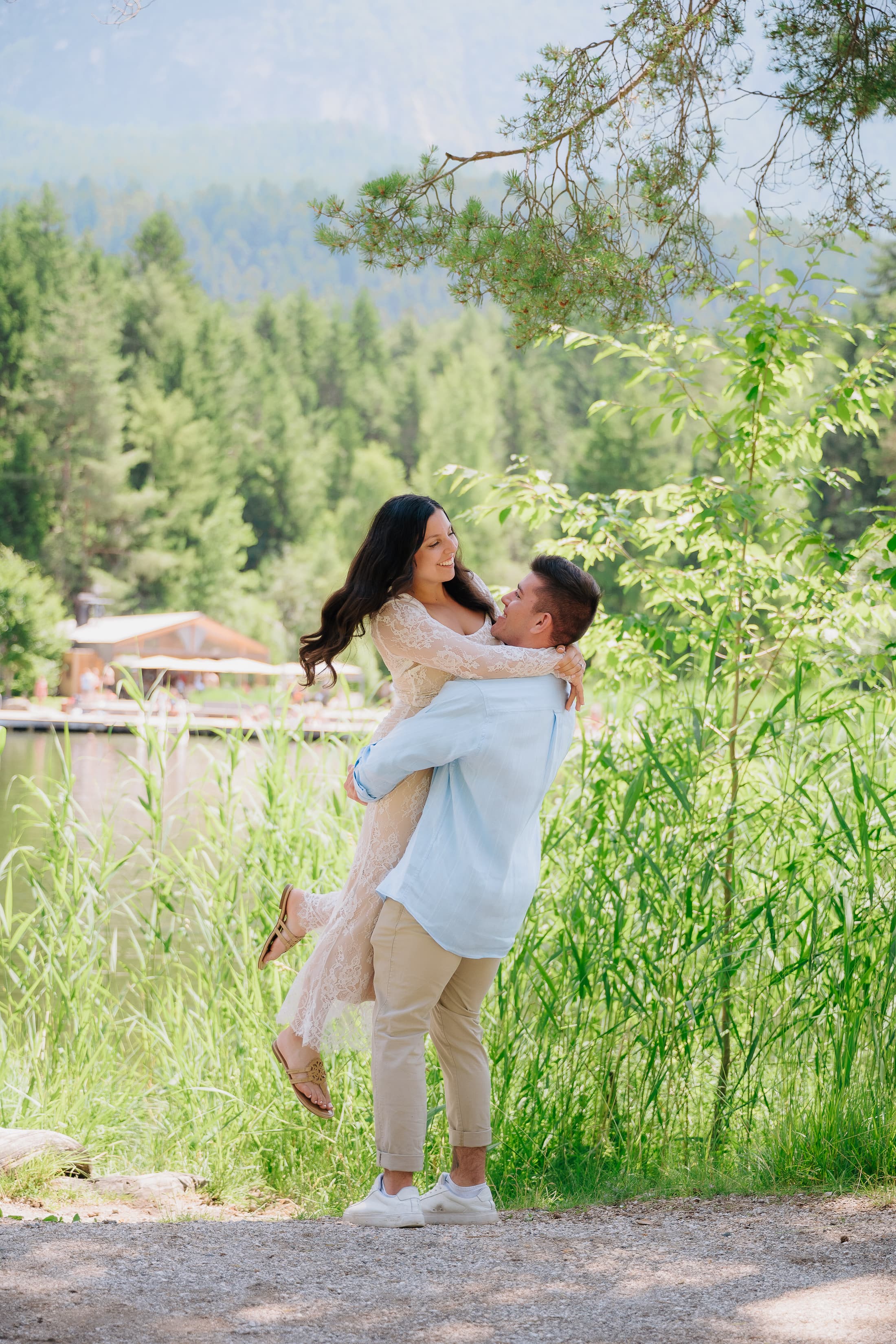 Nicole smiling as JT holds her in a sunny field.