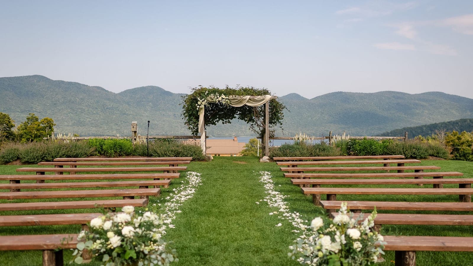 An outdoor ceremony arch on the lawn at Mountain Top Resort, with the Green Mountains and lake behind.