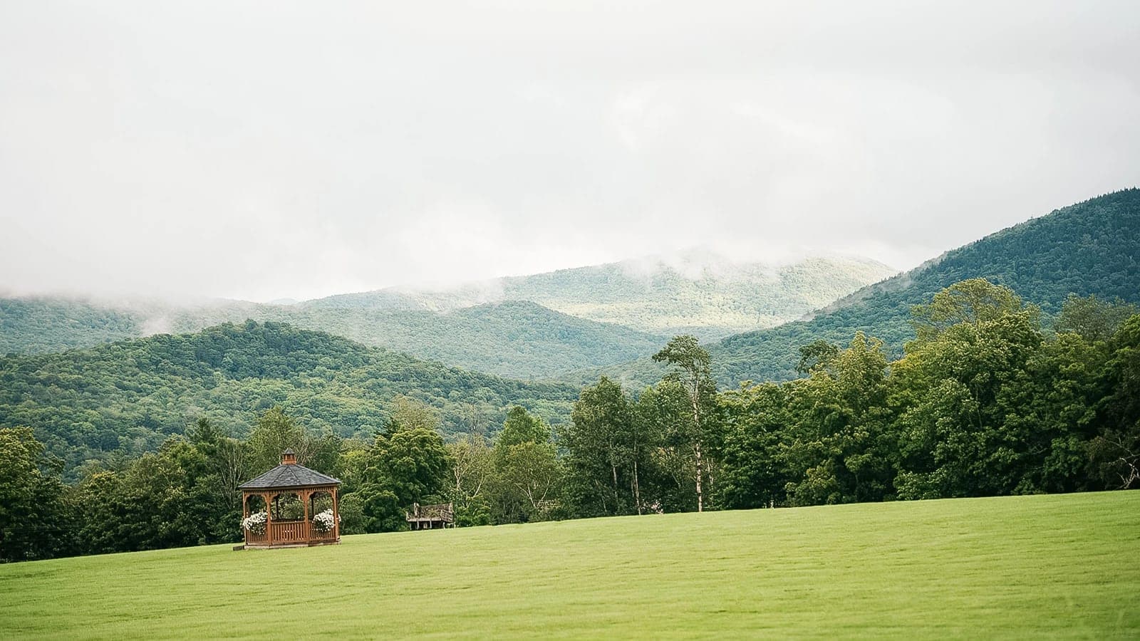 A gazebo on the open meadow with misty Green Mountains behind.