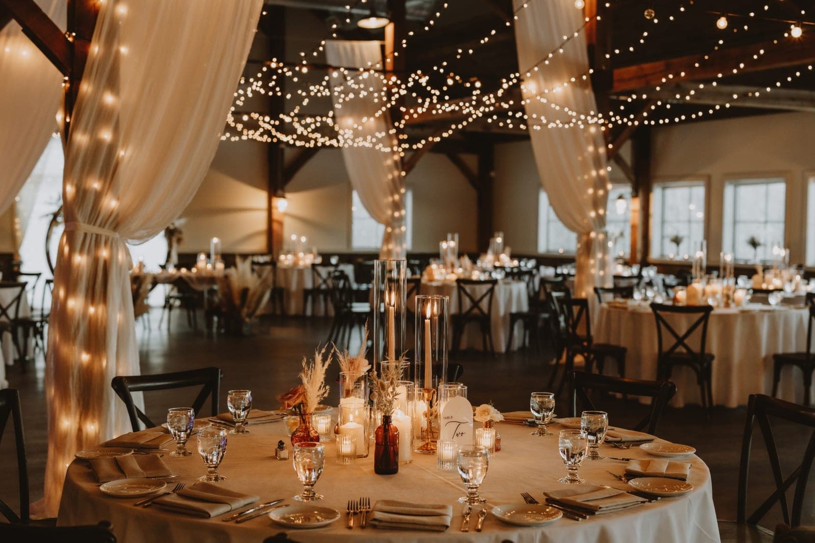 The reception barn set with candlelit tables and string lights.
