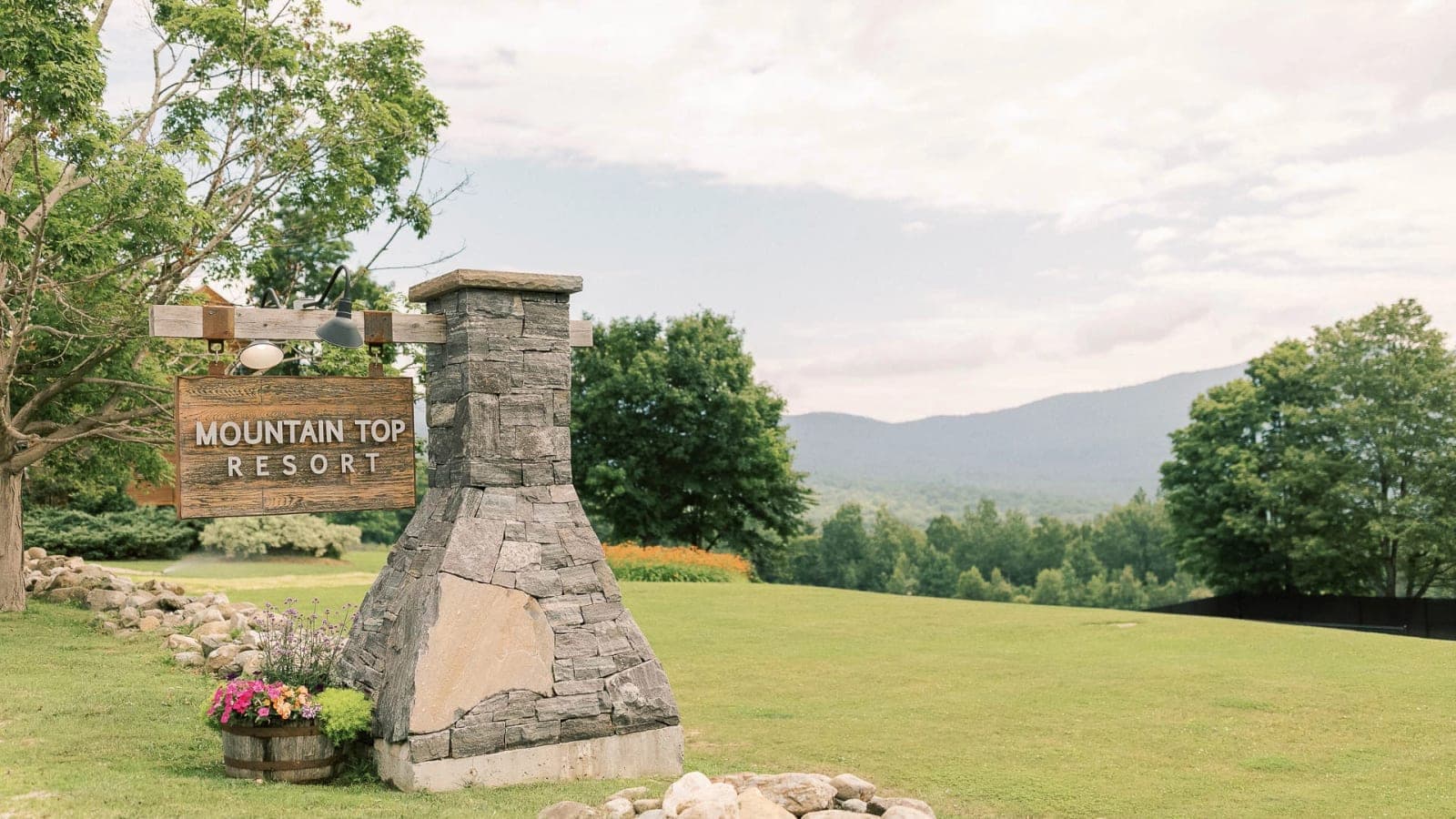 The Mountain Top Resort stone entrance sign with mountains in the distance.